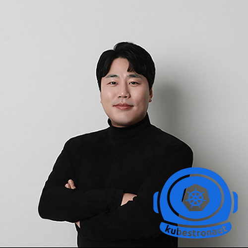 A man in a black turtleneck has his arms crossed, smiling and looking off to the side. (Captioned by AI)